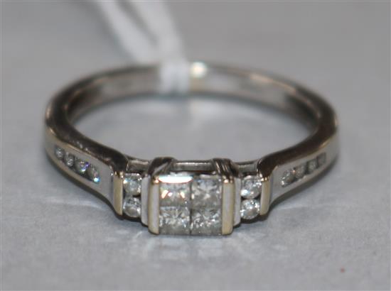 A modern 18ct white gold and Princess cut diamond set dress ring, with diamond set shoulders, size O.